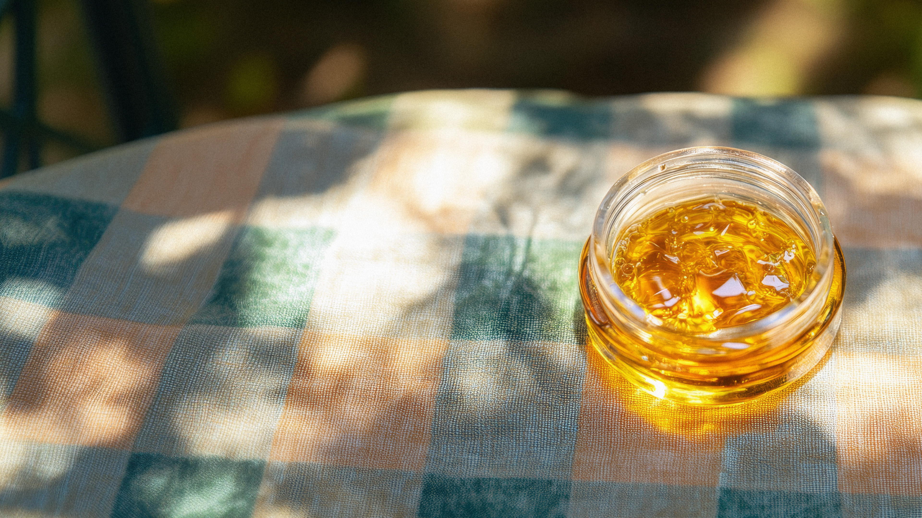 A hand holding a rechargeable vape unit in the woods.